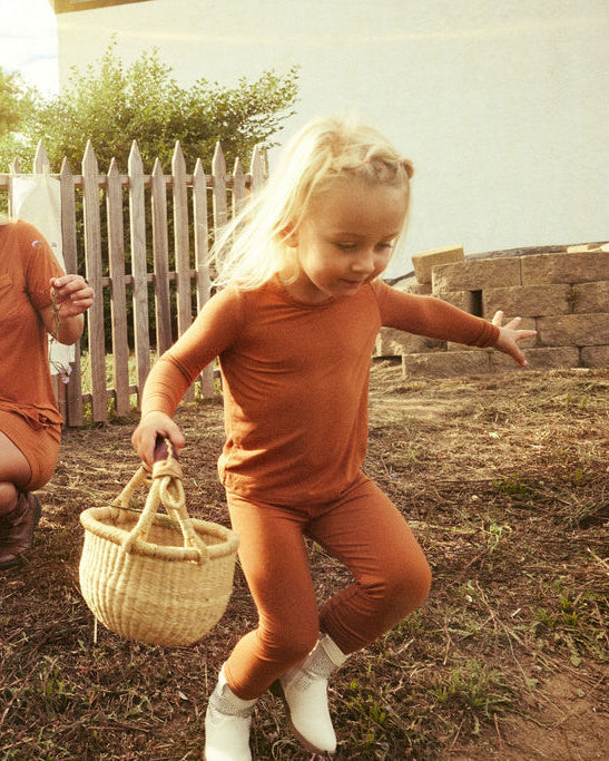 Woman and two children in matching Canyon Clay Two-Piece outdoors with a wooden fence and clothesline in the background.