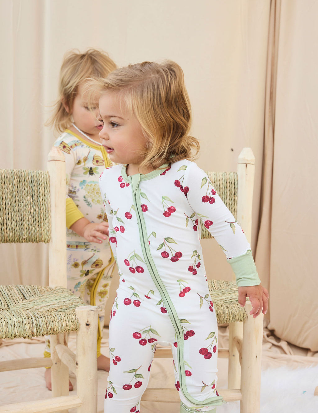 Two children wearing hand-painted pajamas standing in a softly lit room.
