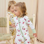 Two children wearing hand-painted pajamas standing in a softly lit room.