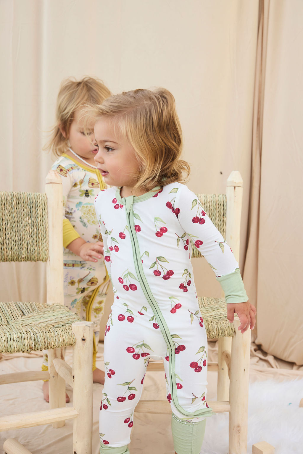 Two children wearing hand-painted pajamas standing in a softly lit room.