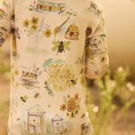 Child wearing a onesie with bee and honeycomb patterns in a natural setting