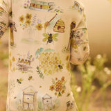 Child wearing a onesie with bee and honeycomb patterns in a natural setting