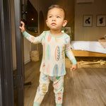 Child in hand-painted surfboard pajamas standing in a doorway with a bedroom in the background
