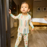 Child in hand-painted surfboard pajamas standing in a doorway with a bedroom in the background