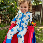Child in a blue tractor onesie sliding down a red slide outdoors