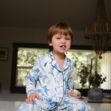 Child in blue floral pajamas sitting on a kitchen counter with a bowl.