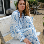 Woman in a blue and white patterned pajama set sitting on a chair outdoors.