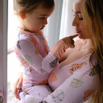 Woman using a nursing pillow with a child standing close by
