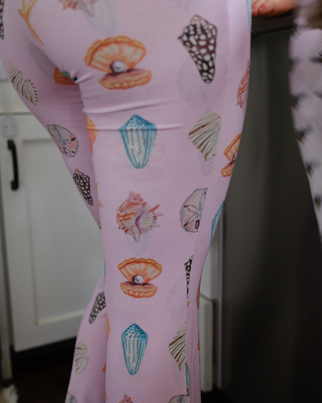 Pink leggings with shell pattern worn by a person, blurred background