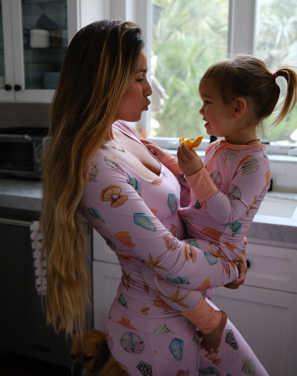 Woman and child in matching pajamas standing in a kitchen.