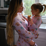 Woman and child in matching pajamas standing in a kitchen.