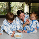 Woman and two children in matching pajamas sitting on a kitchen counter with a bowl of popcorn.